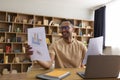 Virtual meeting. Happy arab man having video call, checking documents with diagrams and using laptop Royalty Free Stock Photo