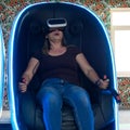 Virtual reality attraction, virtual glasses and entertainment in playrooms for children. A woman sits in a 5d neon chair Royalty Free Stock Photo