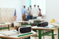 Virtual reality headsets on tables with teacher and high school students standing behind