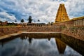 Virupaksha temple of Hampi with the reflection on water surface under open blue sky.