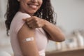 Happy young pretty african american female showing arm with band-aid after getting vaccination