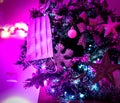 Virus protection mask on a christmas tree in fuchsia light