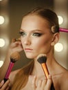 Visage course, professional make up. Woman getting powder on skin with brushes, makeup. Hands apply makeup on model face Royalty Free Stock Photo