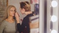 Visage - makeup artist and blonde model near mirror in the dressing room Royalty Free Stock Photo