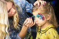 Visagist painting the face of a little girl