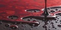 Viscous red liquid dripping and pooling on a dark reflective surface with swirling patterns Royalty Free Stock Photo