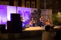 View of an evening and outdoor musical event, jazz music concert, band with drummer, guitarist, bass and female vocalist