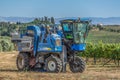 View of a grape harvesting machine on agricultural fields with vineyards