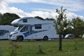 Motorhomes standing on grass and between trees