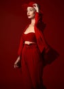 Vision, fashion and a woman in a hat on a red background in studio for elegant or trendy style. Aesthetic, beauty and