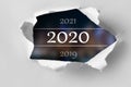 Vision 2020 goal written behind a torn paper. Top view of white torn paper and the text `2020` on a background.