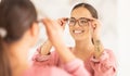 Vision, mirror and happy woman trying on glasses to choose a new frame at an optometry store. Smile, eyewear and lady