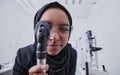 Vision, optometrist and woman with retinoscope in hospital for examination. Eye test, healthcare and muslim doctor or