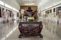 The golden incense pot in front of the marble laughing Buddha statues