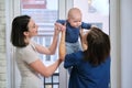 Visit of doctor pediatrician home, mother with baby son talking with doctor