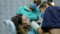 Visit to the dentist. Orthodontist doctor with assistent sets up iron braces for a woman with a dental fixator