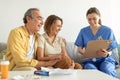 Visit to patient. Nurse talking with senior couple, holding clipboard in conversation with aged man and woman Royalty Free Stock Photo