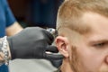 Visiting barbershop. Close up shot of a young caucasian man getting trendy haircut. Barber using professional electric Royalty Free Stock Photo