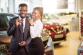 Visiting car dealership. couple holding key of their new car, looking at camera Royalty Free Stock Photo