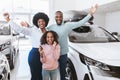 Excited Afro family showing key, shouting WOW, feeling happy over buying new auto, raising hands up at car dealership Royalty Free Stock Photo