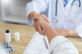 Visiting a doctor concept A male doctor sitting at his desk and checking hand with his patient cheerfully Royalty Free Stock Photo