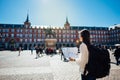 Visiting famous landmarks and places.Cheerful female traveler at famous Plaza Mayor square reading a map