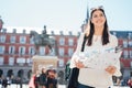 Visiting famous landmarks and places.Cheerful female traveler at famous Plaza Mayor square reading a map. Marid,Spain travel Royalty Free Stock Photo