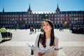 Visiting famous landmarks and places.Cheerful female traveler at famous Plaza Mayor square reading a map. Marid,Spain travel Royalty Free Stock Photo