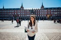 Visiting famous landmarks and places.Cheerful female traveler at famous Plaza Mayor square reading a map. Marid,Spain travel Royalty Free Stock Photo