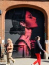 People walking past graffiti street art in Shoreditch, East London England UK Royalty Free Stock Photo