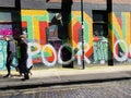 People walking past graffiti street art in Shoreditch, East London England UK Royalty Free Stock Photo