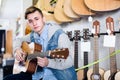 Visitor is choosing quality acoustic guitar Royalty Free Stock Photo