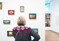 Visitor standing in front of white wall with artworks in museum.