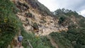 A visitor walking along the cliff and under the Karajia sarcophagi. KARAJIA , PERU - MARCH 31st, 2019