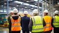 Visitors having guided tour In factory, wearing PPE with Hi Viz vest