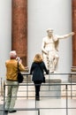 Visitors looking on Roman emperor statue in Pergamon museum in city Berlin at Germany