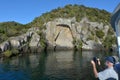 Visitors photographing the iconic Maori Rock Carving at lake Tau