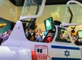 Visitors sit in the cabin of the aircraft simulator and use it under the supervision of an army instructor at the army exhibition