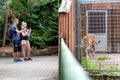 Visitors standing in front of tiger in cage and making photos in zoo