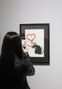 Visitors take photos in a Banksy unauthorized exhibition