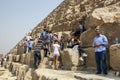 Visitors to the Giza pyramids in Cairo in Egypt climb over the huge sandstone blocks of the Pyramid of Khufu.