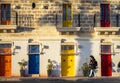 Visitors walk in front of the building with colorful doors at Malta Marsaxlokk