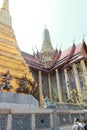 Visitors walking between the beautiful buildings of Wat Phra Kaew temple complex in Bangkok, Thailand