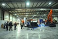 Visitors walking around and looking at vehicles parked in a hangar. Exhibition Heavy Duty. Kyiv, Ukraine