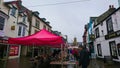 Visitors walking through a local market with traditional houses alongside in a rainy day Royalty Free Stock Photo