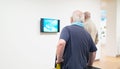 Visitors watching television in museum room.