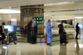 Visitors wearing face masks at luggage carousel, arrival hall. Traveller in protective suit is seen