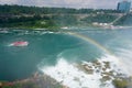 Visitors in yellow raincoats, a rainbow emerging from the mist, and a tour boat sailing through the Niagara Gorge