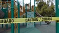 Vista, CA / USA - March 25, 2020: Bi-lingual caution tape ropes of a California playground closed down due to Covid-19