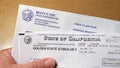 Close up of hand holding a Golden State Stimulus check sent out by